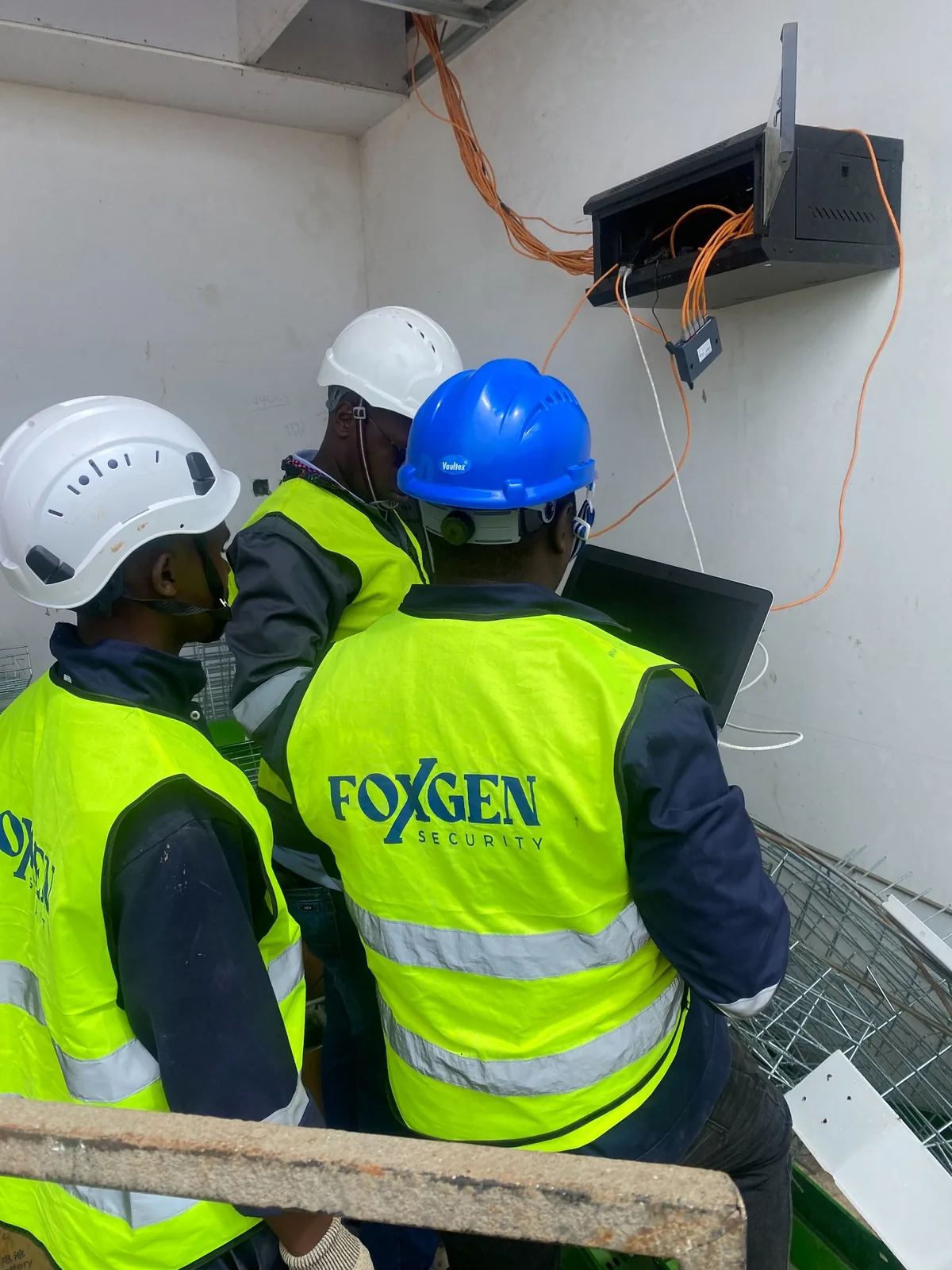 Foxgen technicians working beside a network cabinet and exposed data cabling